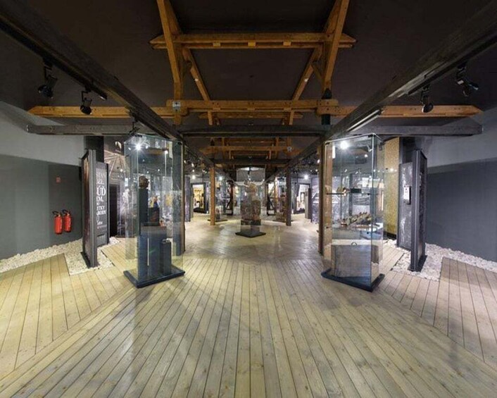 An indoor space with wooden beams, glass display cases, and a polished wooden floor. 4
