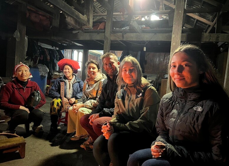 A group of people sitting indoors in a rustic setting with wooden beams and a dimly lit environment. 3