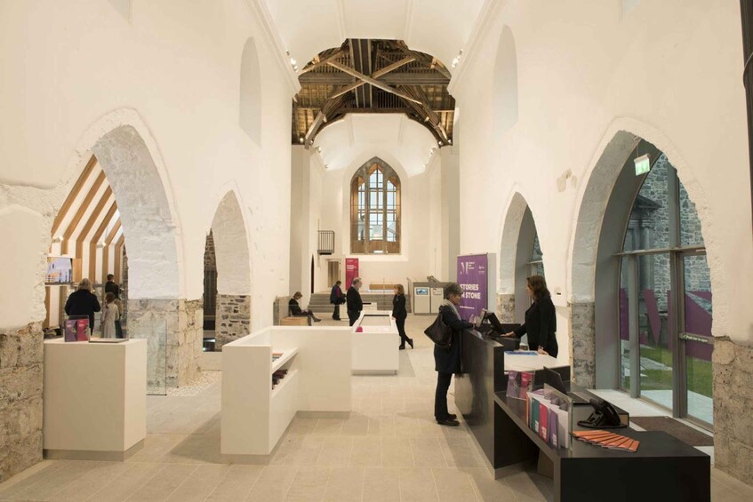 An interior with arched ceilings, stone walls, and a central aisle leading to a window. 2