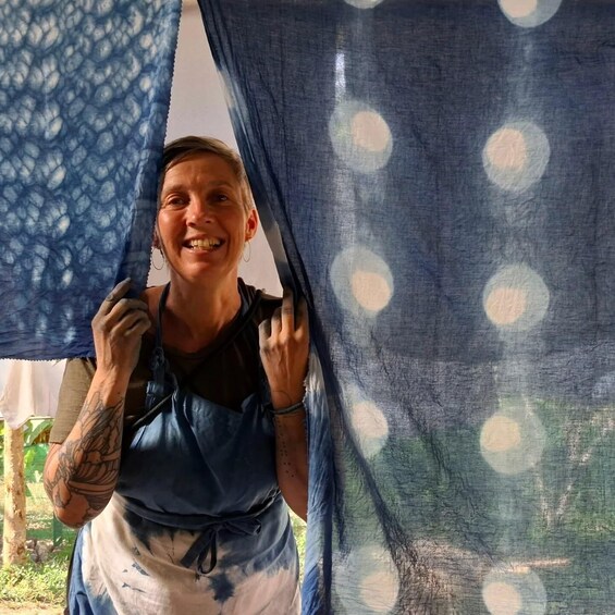 A person standing in front of a blue curtain with a pattern. 1