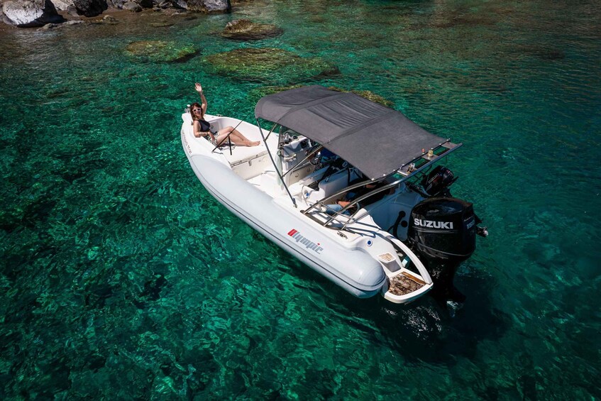 A white inflatable boat with a Suzuki outboard motor, floating on clear turquoise water. 2