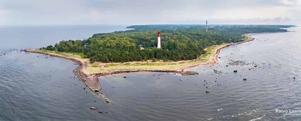 A lighthouse on a small island surrounded by water. 1