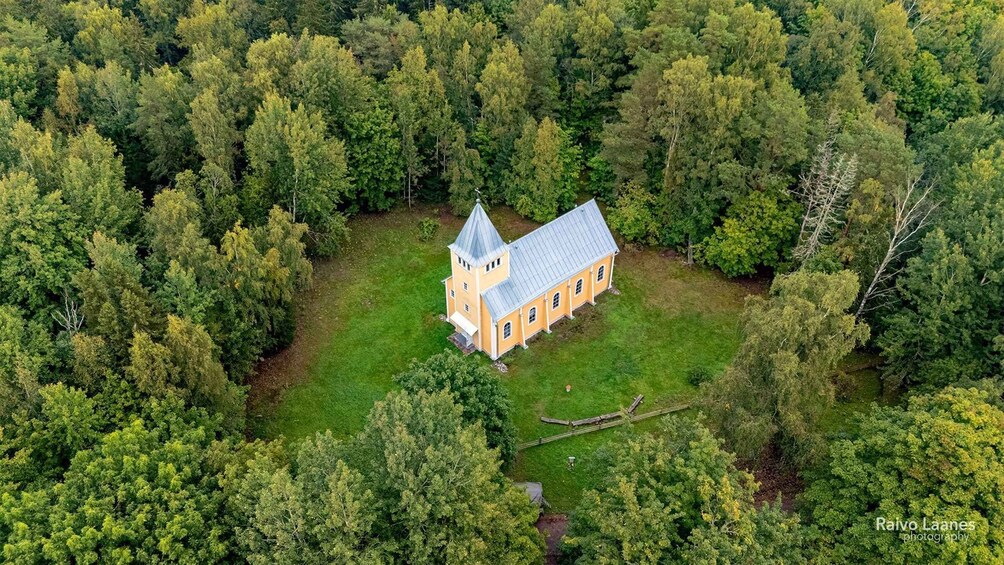An aerial view of a church surrounded by dense forest. 2