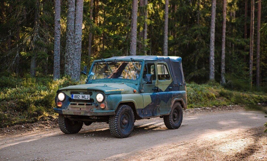 A green off-road vehicle on a forest road. 3