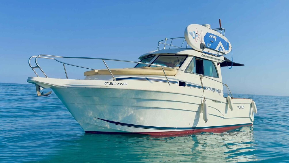 A white boat named 'STARFISHER VENUS' with registration number '6º BI-3-12-25' on calm blue waters. 5