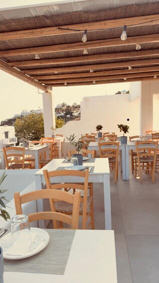 An outdoor café with wooden tables and chairs, potted plants, and a view of the cityscape. 3