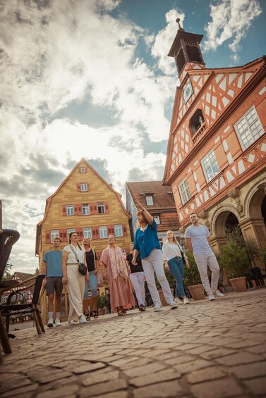 A cobblestone street with historic buildings, including a church with a clock tower. 1