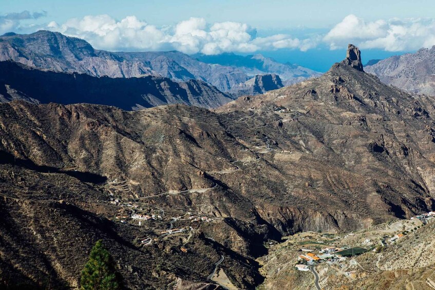 A rugged mountain landscape with a prominent peak, a small settlement at the base, and a clear sky. 1