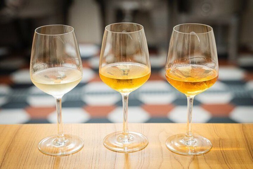 Three wine glasses on a wooden table with a checkered tablecloth. 4