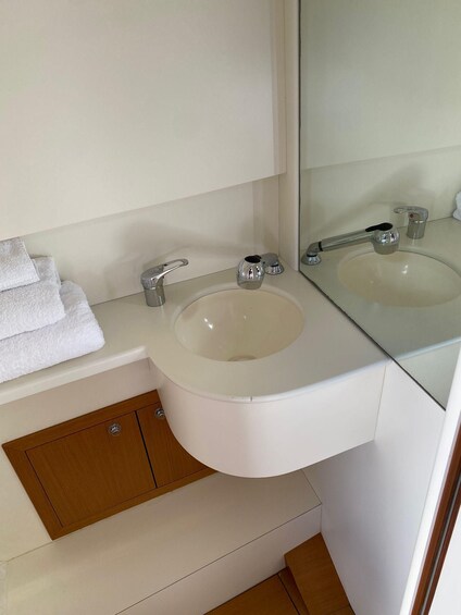 A bathroom with a white sink, two faucets, a mirror, and a towel rack. 5