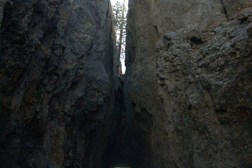 A narrow canyon with steep rock walls and sparse vegetation. 3
