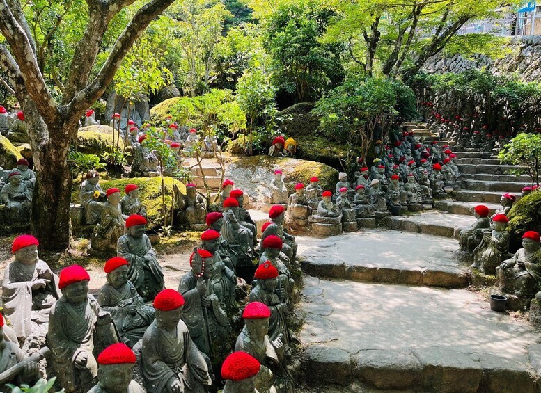 Un jardín con estatuas de piedra de monjes con sombreros rojos, dispuestos en filas y sentados en escalones. 1
