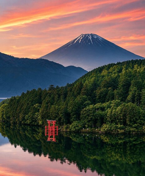 A serene lake with a reflection of a red structure, a forested hill, and a snow-capped mountain in the background. 3
