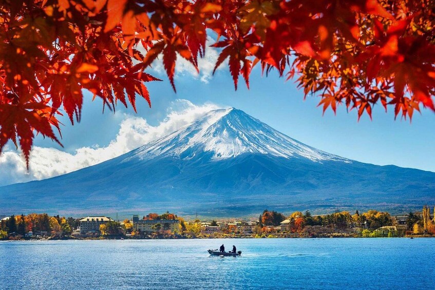 A lake with a boat, a snow-capped mountain, and autumn foliage. 5