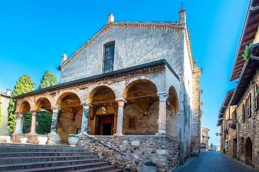 A historic building with a stone facade, arched portico, and a bell tower. 2