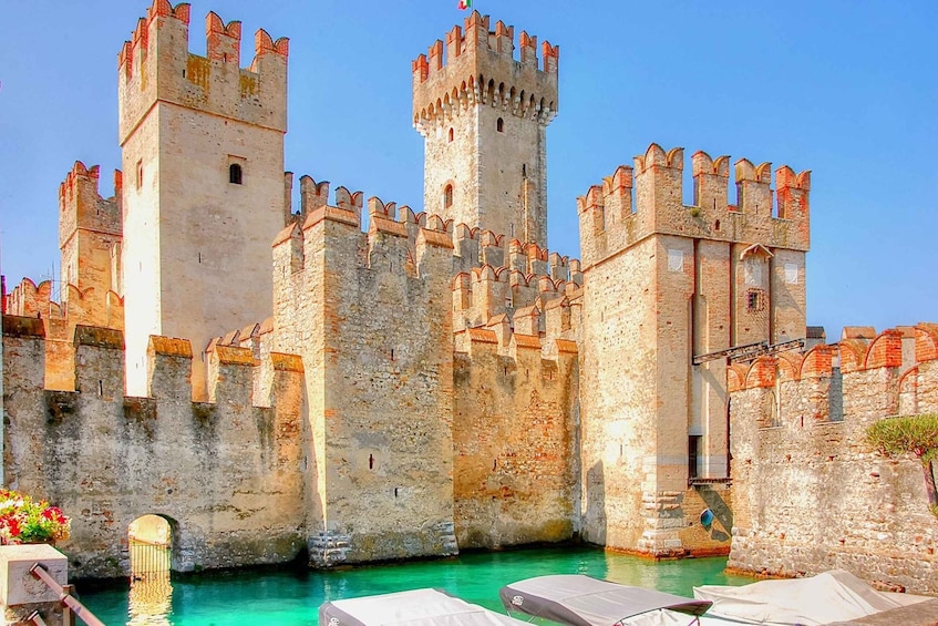 A historic castle with multiple towers, a moat, and a clear sky. 4