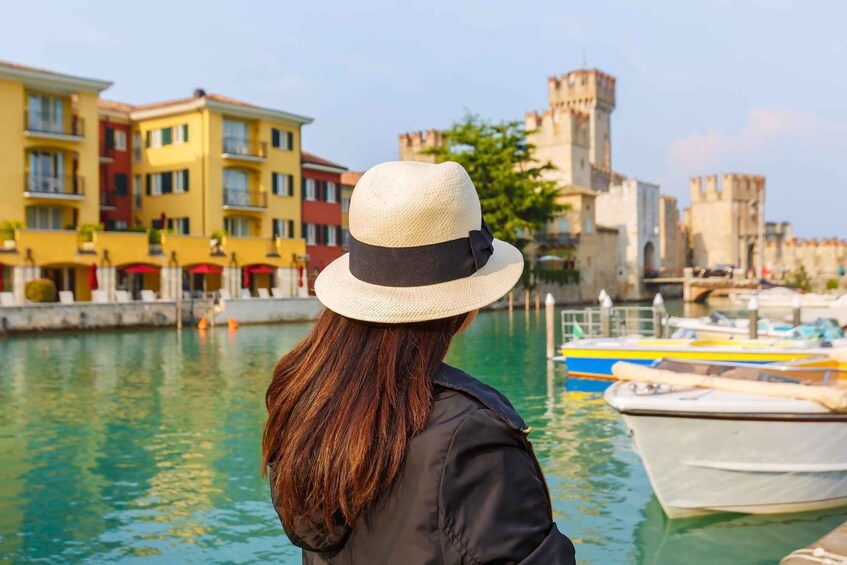 A person with a hat overlooking a canal with boats and colorful buildings in the background. 1