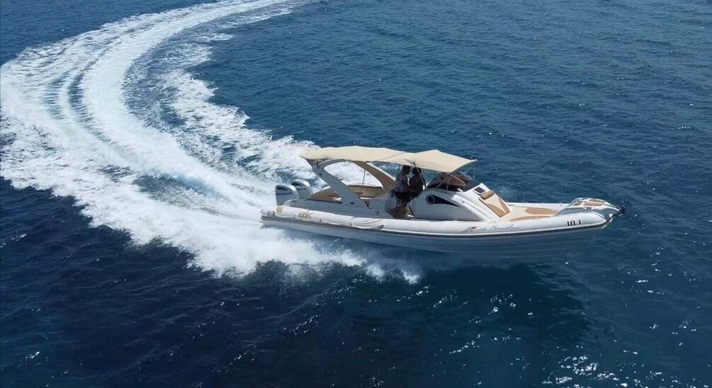 A speedboat with two people on board, creating a wake in the ocean. 1