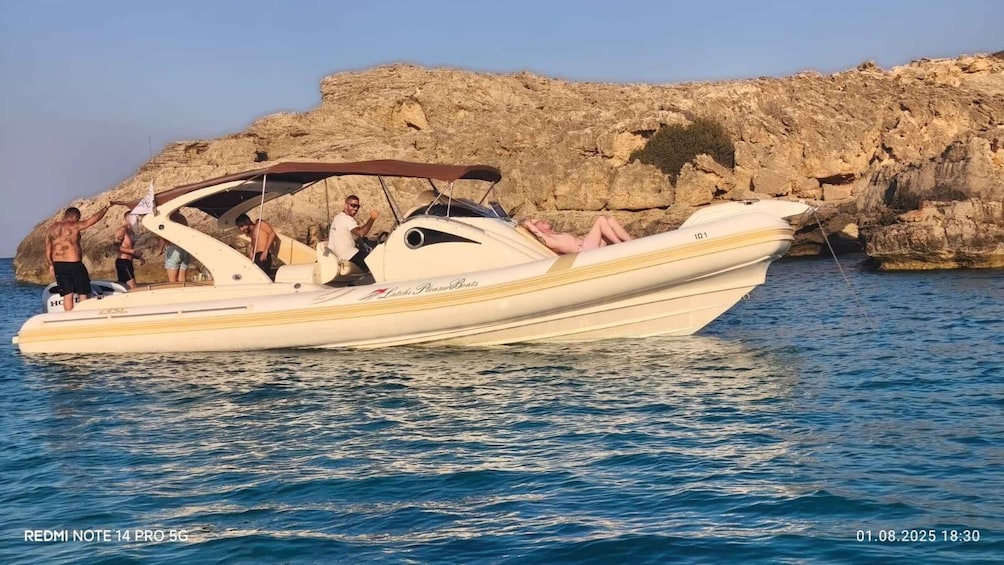 A white motorboat with people on board, anchored near rocky cliffs. 5
