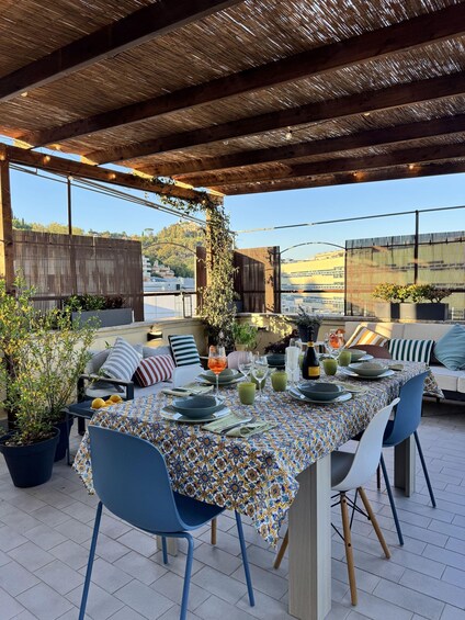 An outdoor dining area with a covered patio, a table set for a meal, and potted plants. 3