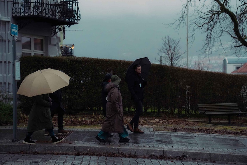 A group of people walking on a wet sidewalk, some holding umbrellas. 2