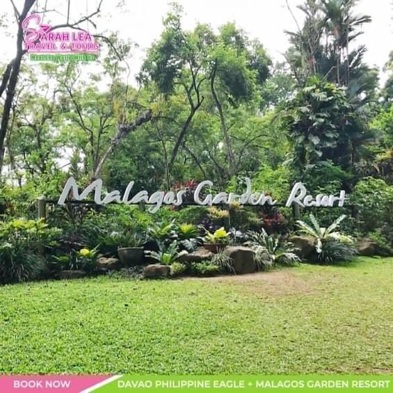 A sign for Malagas Garden Resort surrounded by lush greenery and a well-maintained lawn. 3