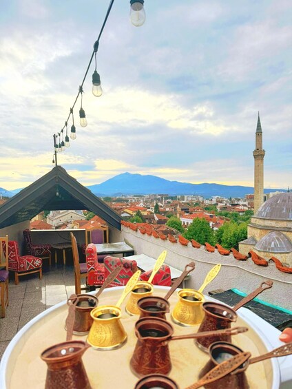 A rooftop terrace with traditional Turkish tea set, a mosque, and a mountain in the background. 4