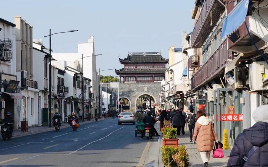 A street with traditional architecture, pedestrians, and vehicles. 3