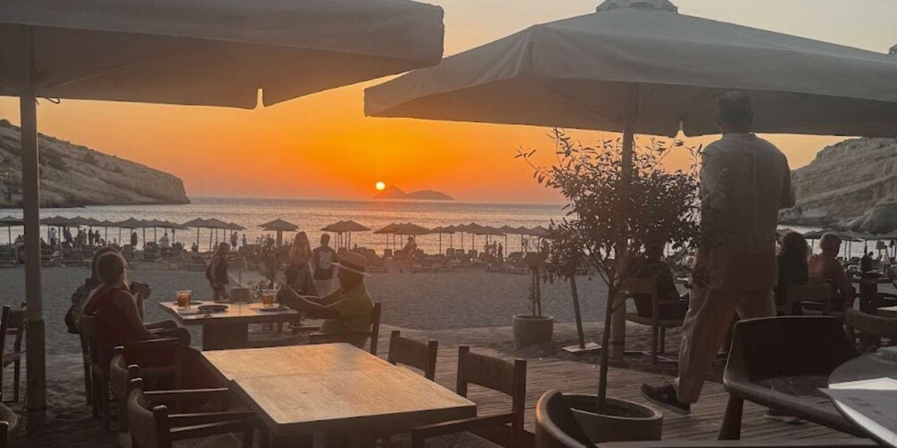 A beachside restaurant with tables and umbrellas during sunset. 2