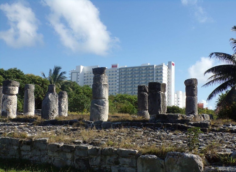 Ancient stone pillars, a stone wall, and a modern building in the background. 3
