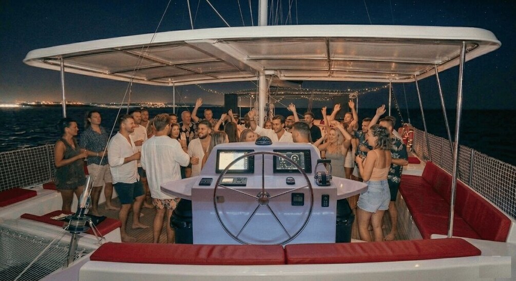 A group of people on a boat with a steering wheel and a canopy overhead. 5