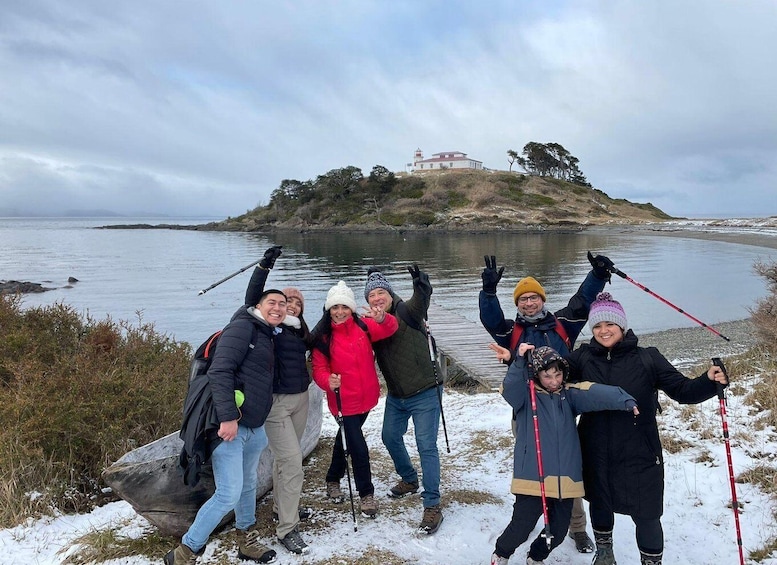 A group of people posing by a lake with a lighthouse in the background. 1
