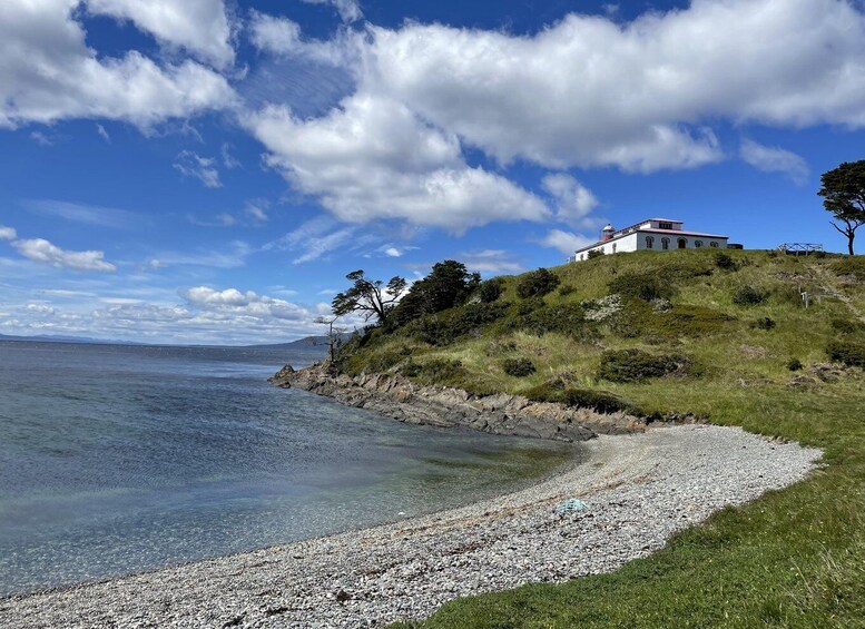 A coastal landscape with a white building on a grassy hill, clear blue sky, and calm sea. 3