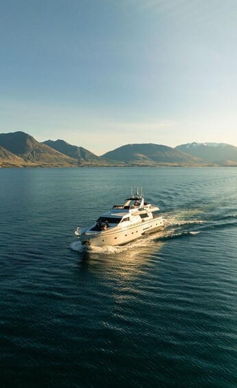 A yacht on a calm sea with mountains in the background. 1