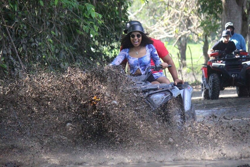 A person riding a motorcycle through a muddy area, splashing mud. 4