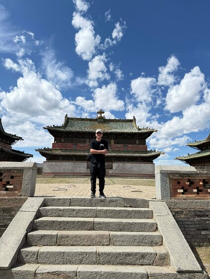 A person standing on stone steps in front of a traditional building with ornate architecture. 5