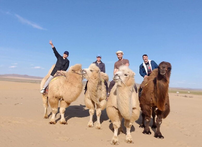 A group of people riding camels in a desert landscape. 1