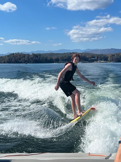 A person wakeboarding on a lake with mountains in the background. 2