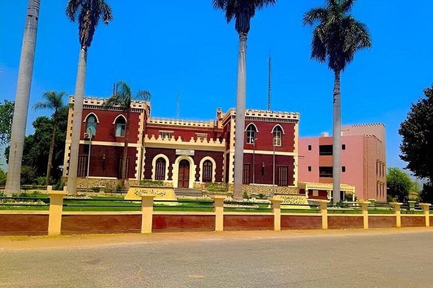 A red building with arched windows and a pink building in the background. 2