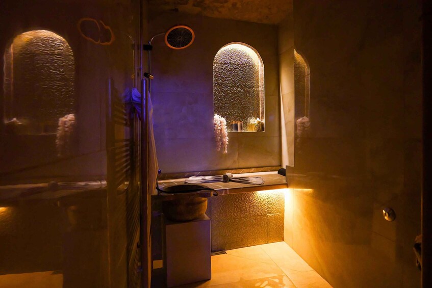 A dimly lit bathroom with a shower, a sink, and a mirror. 3