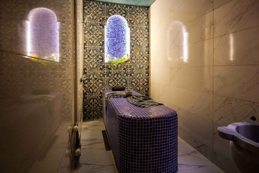 A bathroom with patterned tiles, a blue-tiled bench, and a window with a view. 5