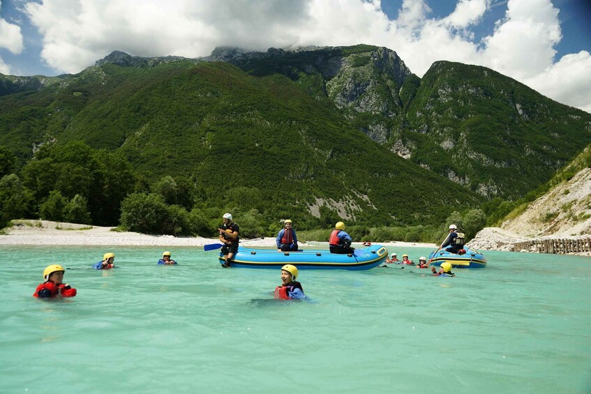 People in a blue raft on a turquoise river with mountains in the background. 3