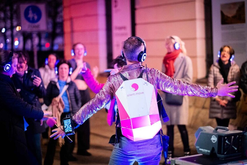 A person with a backpack labeled 'silent.move' gesturing towards a crowd. 3