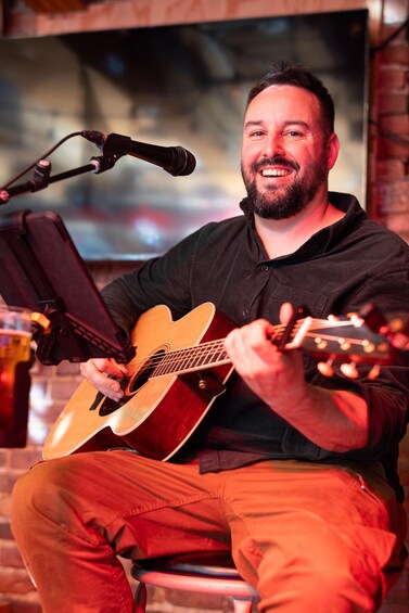 A person playing an acoustic guitar with a microphone stand nearby. 5