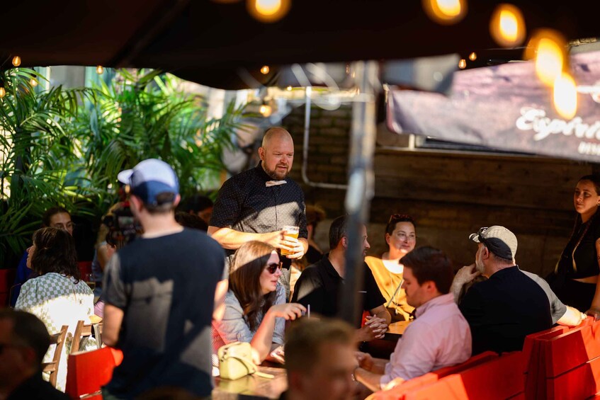 A person speaking to an audience at an outdoor event with tables and chairs. 4