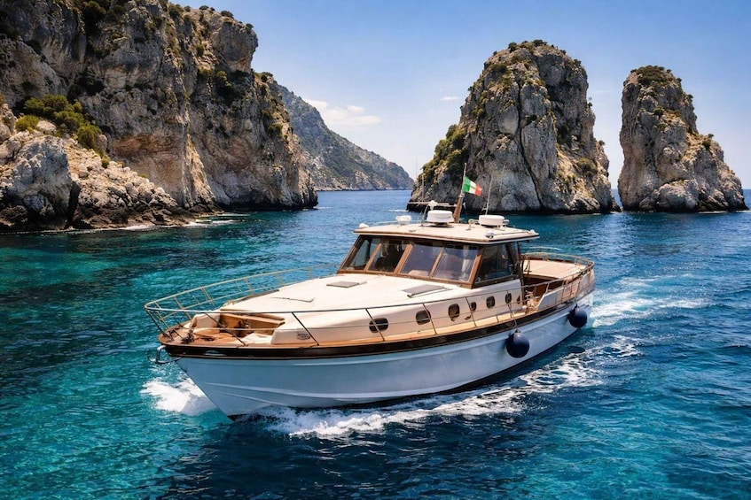 A white boat with a flag, moving through clear blue waters between rocky cliffs. 1