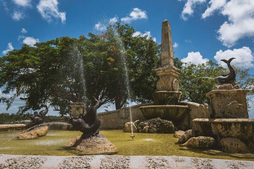 A fountain with water jets, a tall obelisk, and a sculpture of a bird. 4
