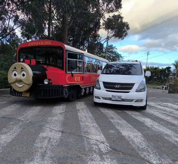 A red and white bus labeled 'ZIPATOURS' and a white car parked on a road with trees and a cloudy sky in the background. 4