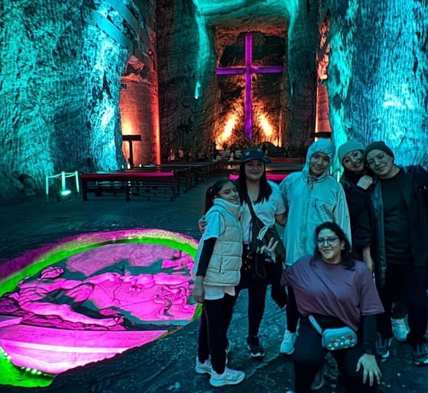 A group of people in a cave with illuminated walls and a cross. 3