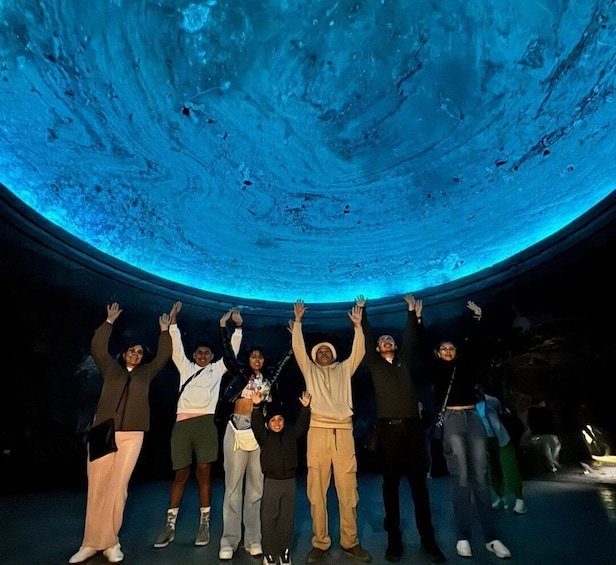 A group of people standing under a large, illuminated dome structure. 1